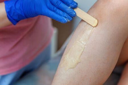 Beautician makes epilation close-up girl on her leg. Shugaring.の写真素材
