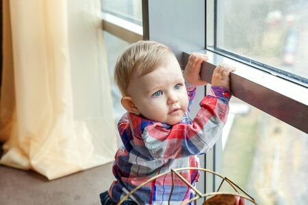 Cute smiling baby standing at home near windowの写真素材