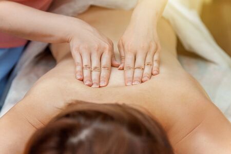 Close-up of young beauty brunette woman getting body back massage treatment in spa salon. Spa skin and body care. Skincare cleansing cosmetic health spa relax pleasure conceptの写真素材