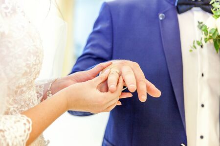 Bride and groom marriage hands with wedding rings. Bride hand putting wedding ring on groom finger. Declaration of love, spring. Wedding card greeting. Wedding day moments ceremony detailsの写真素材