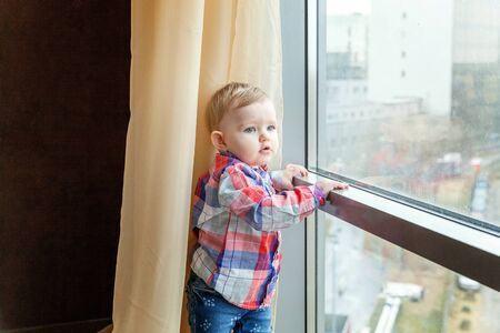 Cute smiling baby standing at home near window