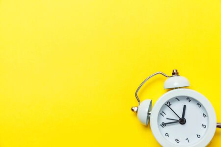 Ringing twin bell vintage classic alarm clock Isolated on yellow colourful trendy modern background. Rest hours time of life good morning night wake up awake concept. Flat lay top view copy spaceの写真素材