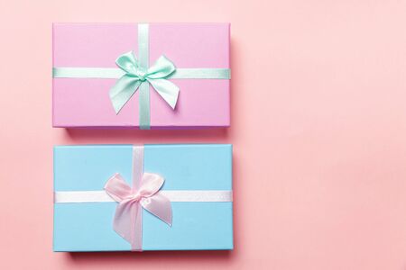 Christmas New Year birthday valentine celebration present romantic concept. Small gift box wrapped pink and blue paper isolated on pink pastel colorful trendy background. Flat lay top view copy spaceの写真素材