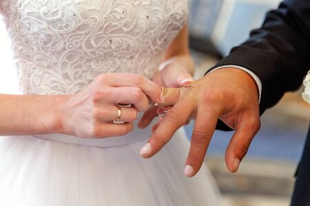Bride and groom marriage hands with wedding rings. Bride hand putting wedding ring on groom finger....