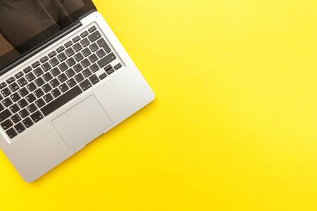 Keyboard laptop computer isolated on yellow desk background. Modern Information technology and...