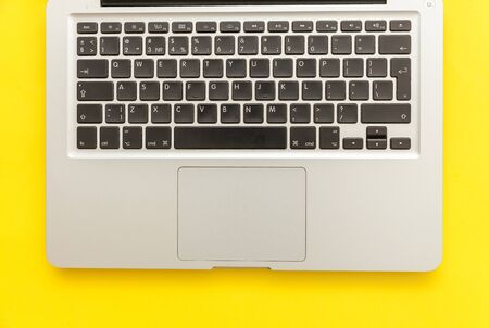 Keyboard laptop computer isolated on yellow desk background. Modern Information technology and sofware advances. Freelance home office programmer or designer workspace conceptの写真素材