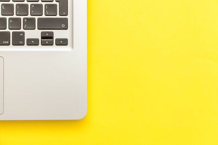 Keyboard laptop computer isolated on yellow desk background. Modern Information technology and sofware advances. Freelance home office programmer or designer workspace conceptの写真素材
