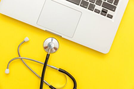 Stethoscope keyboard laptop computer isolated on yellow background. Modern medical Information technology and sofware advances concept. Computer and gadget diagnostics and repair. Flat lay top viewの写真素材