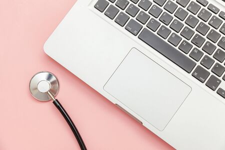 Stethoscope keyboard laptop computer isolated on pink background. Modern medical Information technology and sofware advances concept. Computer and gadget diagnostics and repair. Flat lay top viewの写真素材