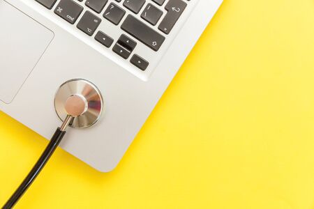 Stethoscope keyboard laptop computer isolated on yellow background. Modern medical Information technology and sofware advances concept. Computer and gadget diagnostics and repair. Flat lay top viewの写真素材