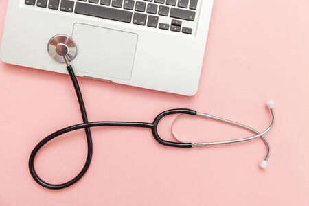 Stethoscope keyboard laptop computer isolated on pink background. Modern medical Information technology and sofware advances concept. Computer and gadget diagnostics and repair. Flat lay top viewの写真素材