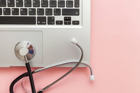 Stethoscope keyboard laptop computer isolated on pink background. Modern medical Information technology and sofware advances concept. Computer and gadget diagnostics and repair. Flat lay top viewの写真素材