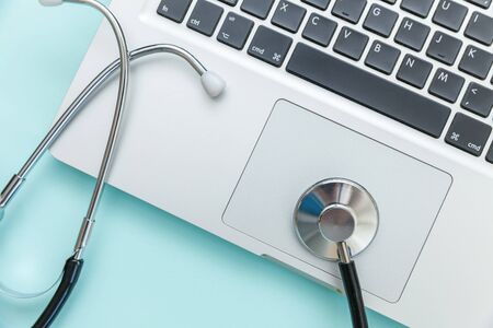 Stethoscope keyboard laptop computer isolated on blue background. Modern medical Information technology and sofware advances concept. Computer and gadget diagnostics and repair. Flat lay top viewの写真素材