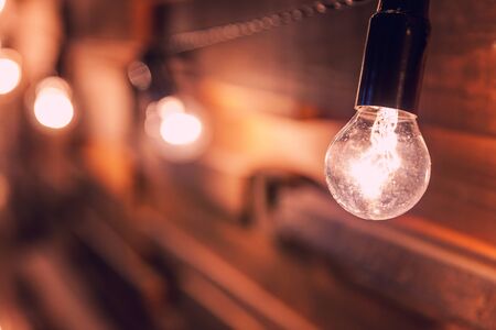 Modern dark classical style interior design apartment with retro lamps hanging light bulbs background. Wooden planks with lamps. Decorated interior room with gold lights. Copy space mockup posterの写真素材