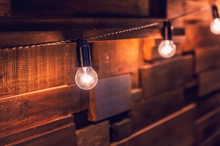 Modern dark classical style interior design apartment with retro lamps hanging light bulbs background. Wooden planks with lamps. Decorated interior room with gold lights. Copy space mockup posterの写真素材