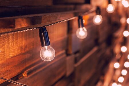 Modern dark classical style interior design apartment with retro lamps hanging light bulbs background. Wooden planks with lamps. Decorated interior room with gold lights. Copy space mockup posterの写真素材