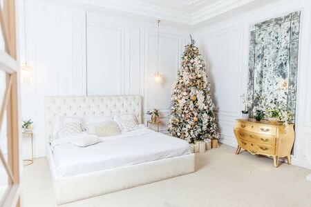 Classic christmas New Year decorated interior room New year tree. Christmas tree with golden ornament decorations. Modern white classical style interior design apartment. Christmas eve at homeの写真素材