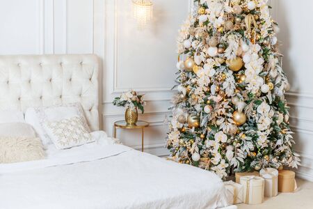 Classic christmas New Year decorated interior room New year tree. Christmas tree with golden ornament decorations. Modern white classical style interior design apartment. Christmas eve at homeの写真素材