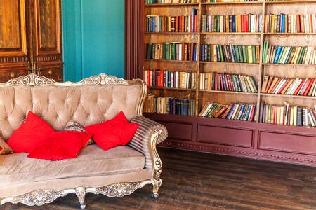 Luxury classic interior of home library. Sitting room with bookshelf, books, arm chair, sofa and fireplace. Clean and modern decoration with elegant furniture. Education read study wisdom conceptの写真素材