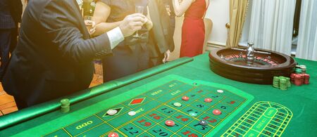 Group of people behind roulette gambling table in luxury casino. Friends playing poker at roulette...