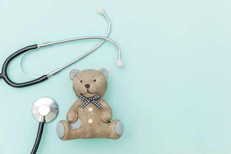 Simply minimal design toy bear and medicine equipment stethoscope isolated on pastel blue background. Health care children doctor concept. Pediatrician symbol. Flat lay top view copy spaceの写真素材