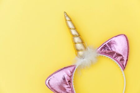 Kawaii unicorn concept. Simply flat lay design Halloween party accessory unicorn horn hairband isolated on yellow colorful background. Fantasy rainbow horse symbolの写真素材