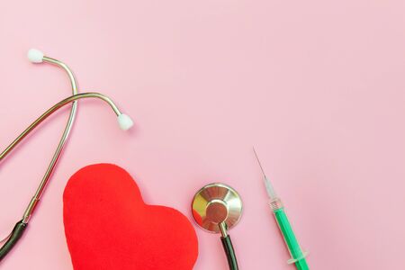 Simply minimal design with medicine equipment stethoscope or phonendoscope syringe and red heart isolated on trendy pastel pink background. Instrument device for doctor. Health care life insurance conceptの写真素材