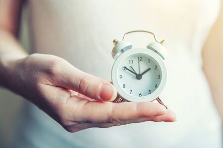 Female woman hands holding ringing twin bell vintage classic alarm clock. Rest hours time of life...