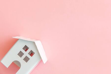 Simply design with miniature white toy house isolated on pink pastel colorful trendy background. Mortgage property insurance dream home concept. Flat lay top view copy spaceの写真素材