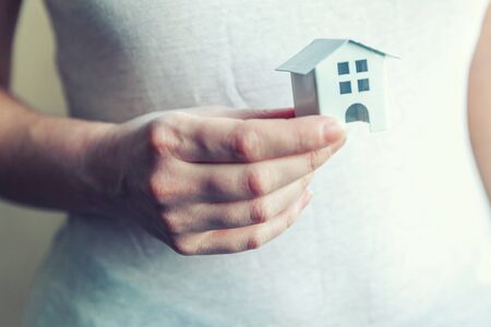 Female woman hands holding small miniature white toy house. Mortgage property insurance dream moving home and real estate conceptの写真素材