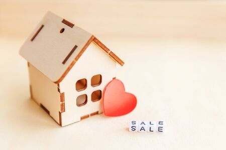 Miniature toy model house with inscription SALE letters word on wooden backdrop. Eco Village abstract environmental background. Real estate mortgage property insurance sweet home ecology rent conceptの写真素材