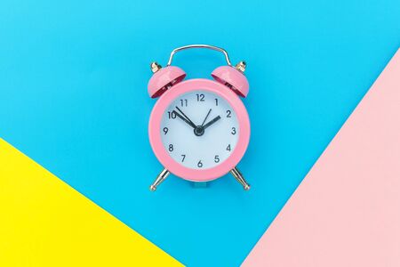 Ringing twin bell classic alarm clock isolated on blue yellow pink pastel colorful geometric...