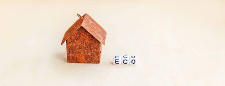 Miniature toy model house with inscription ECO letters word on wooden backdrop. Eco Village abstract environmental background. Ecology zero waste social responsibility recycle bio home concept. Bannerの写真素材
