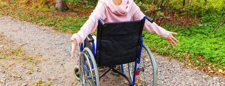 Young happy handicap woman in wheelchair on road in hospital park enjoying freedom. Paralyzed girl in invalid chair for disabled people outdoor in nature. Rehabilitation conceptの写真素材