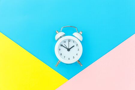 Ringing twin bell classic alarm clock isolated on blue yellow pink pastel colorful geometric...