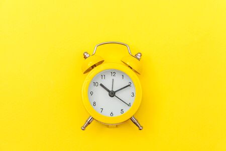 Ringing twin bell vintage classic alarm clock Isolated on yellow colourful trendy modern background....