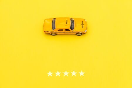 Yellow toy car Taxi Cab and 5 stars rating isolated on yellow background. Smartphone application of...