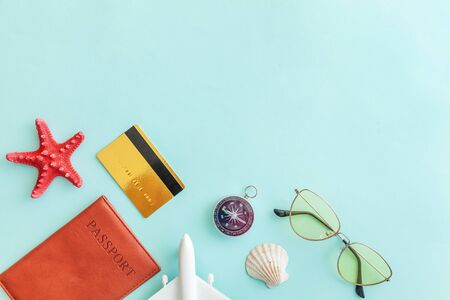 Vacation travel adventure trip concept. Minimal simple flat lay with plane passport sunglasses compass gold credit card shell on blue pastel colourful trendy background. Tourist essentials Copy spaceの写真素材