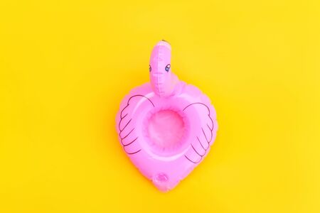 Summer beach composition. Simply minimal design with pink Inflatable flamingo isolated on yellow background. Pool float party, trendy celebrity fashion concept. Flat lay top view copy spaceの写真素材