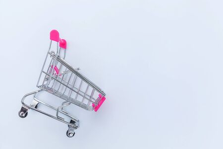 Small supermarket grocery push cart for shopping toy with wheels isolated on white background. Sale buy mall market shop consumer concept. Copy spaceの写真素材