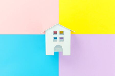 Simply design miniature white toy house isolated on blue yellow pink purple pastel colorful trendy geometric background Mortgage property insurance dream home concept. Flat lay top view copy spaceの写真素材