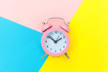 Ringing twin bell classic alarm clock isolated on blue yellow pink pastel colorful geometric background. Rest hours time of life good morning night wake up awake concept. Flat lay top view copy spaceの写真素材