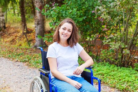 Young happy handicap woman in wheelchair on road in hospital park waiting for patient services....