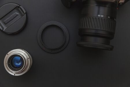 Photographer workplace with dslr camera system and lens on dark black table background. Hobby travel...