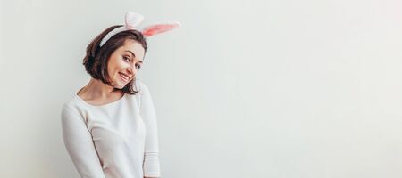Happy Easter holiday celebration spring concept. Young woman wearing bunny ears isolated on white background. Preparation for holiday. Girl looking happy and excited, having fun on Easter day. Bannerの写真素材
