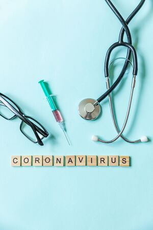 Text phrase Coronavirus syringe eyeglasses and stethoscope on blue pastel background.の写真素材