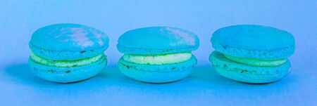 Sweet almond colorful unicorn blue macaron or macaroon dessert cake isolated on trendy blue pastel background. French sweet cookie. Minimal food bakery concept. Bannerの写真素材