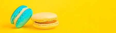 Sweet almond colorful unicorn blue yellow macaron or macaroon dessert cake isolated on trendy yellow...