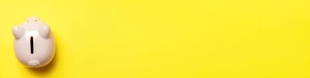 Simply minimal design pink piggy bank isolated on yellow background. Saving investment budget wealth business retirement financial money banking concept. Flat lay top view copy space bannerの写真素材