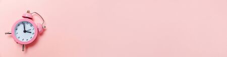 Simply minimal design ringing twin bell classic alarm clock Isolated on pink pastel background. Rest hours time of life good morning night wake up awake concept. Flat lay top view copy space bannerの写真素材